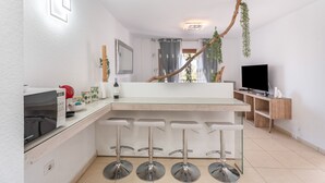 Et moderne køkken med bar, mikroovn, fjernsyn og en plante.