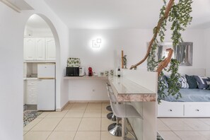 Una cocina moderna con armarios blancos, encimera de mármol y una zona de comedor con taburetes de bar.