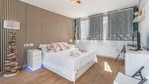 Et moderne soveværelse med seng, natbord, lampe og skrivebord med stol.