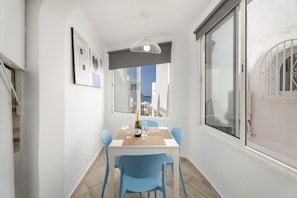 Un coin repas avec une table, des chaises, une bouteille de champagne et une vue par la fenêtre.