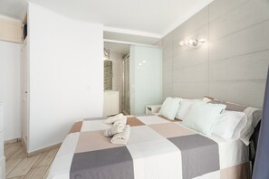 Une chambre d’hôtel moderne avec un grand lit, une salle de bain avec douche et un petit coin salon.