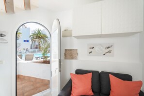 Une pièce avec un canapé, une planche de surf et une vue sur une piscine et des palmiers.