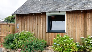 A wooden building with a stone wall in front, a window, and a sign indicating a 25% discount. - Maison “Gîte Mimosas” with Terrace and Wi-Fi (Marzan)