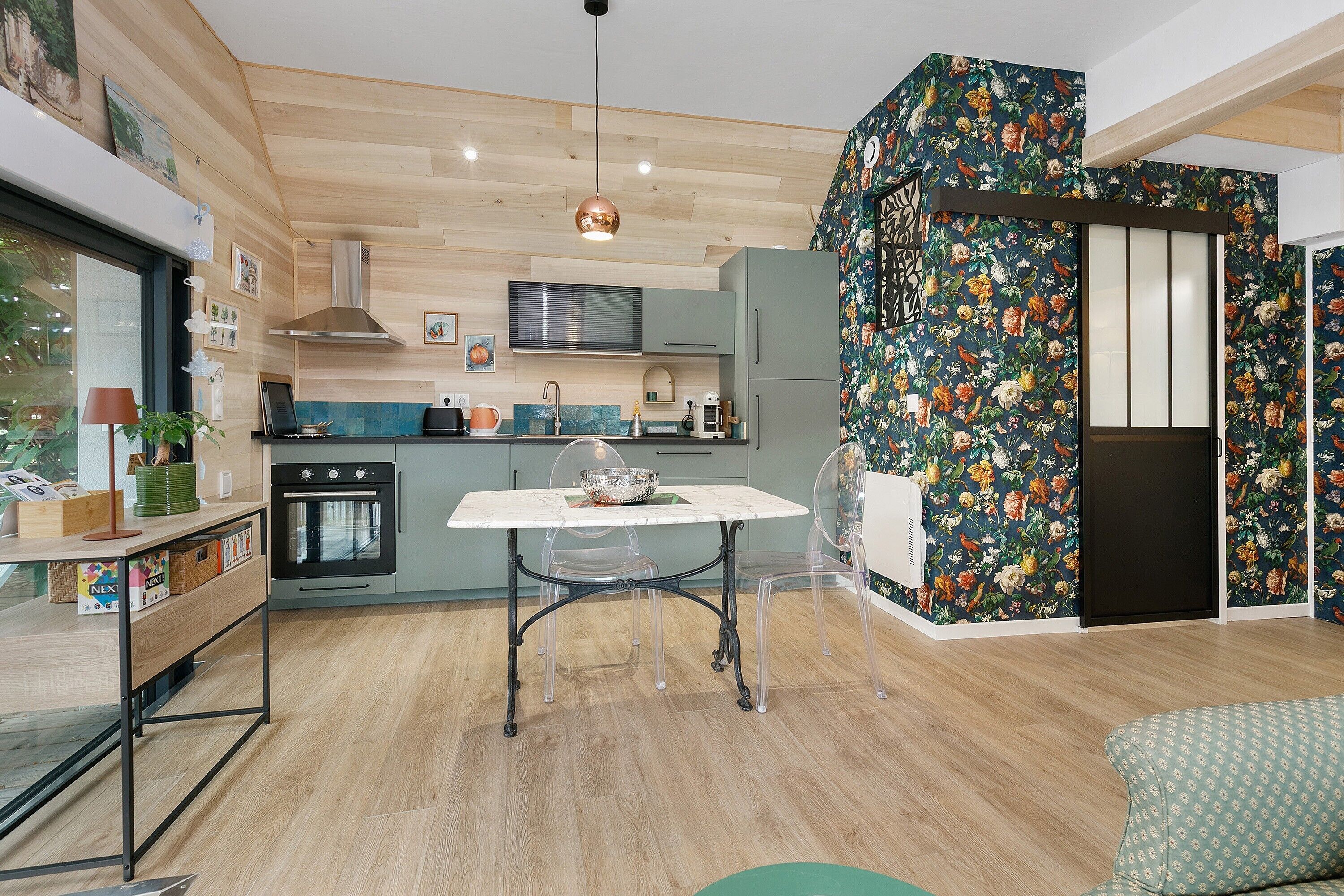 A modern kitchen with wooden cabinetry, a central island, and a dining area with a table and chairs.