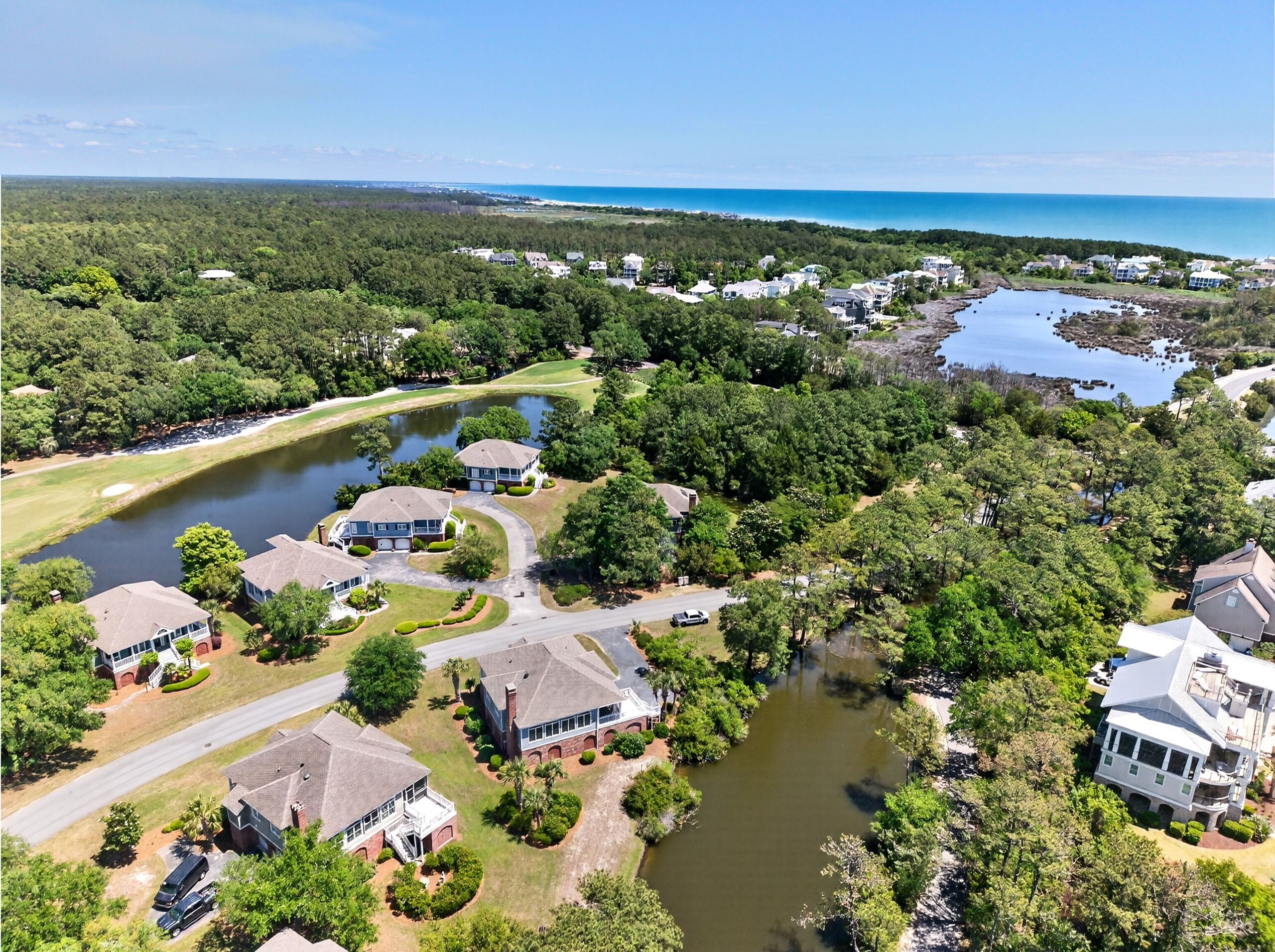 Vue aérienne d’un quartier résidentiel avec des maisons, un lac et un terrain de golf.