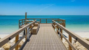 Un muelle de madera que lleva a una playa con agua turquesa cristalina.