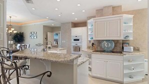 Una cocina con armarios blancos, encimera de granito y una isla central con taburetes de bar.