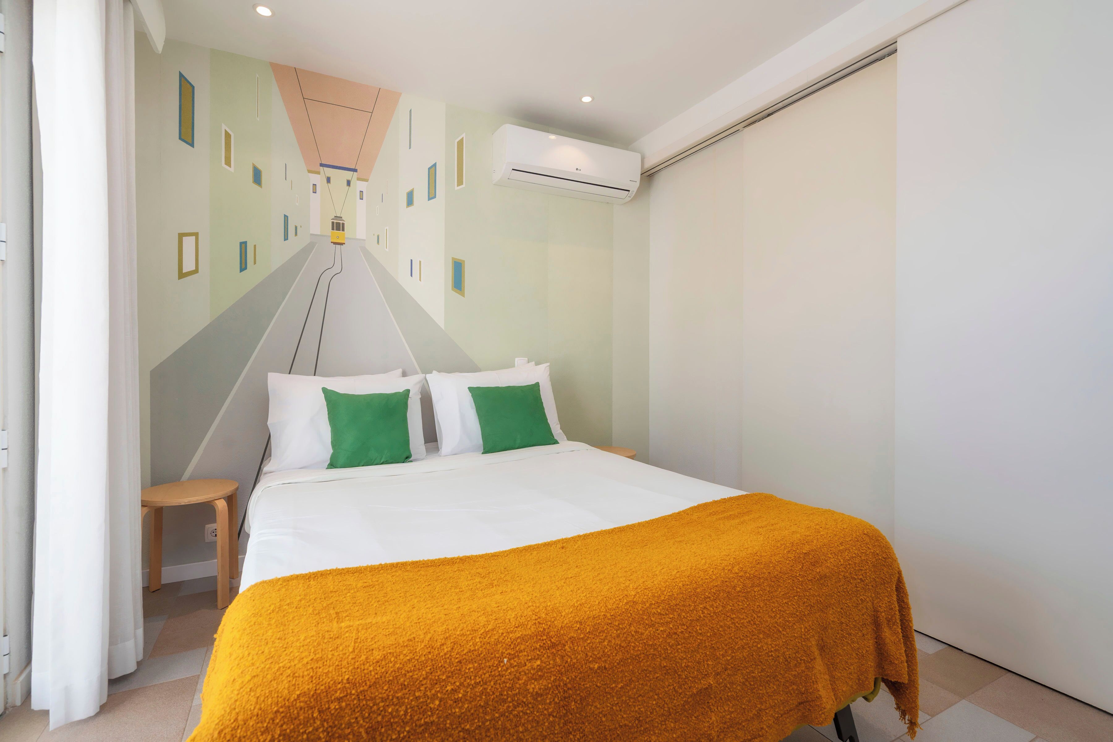 Une chambre d’hôtel avec un lit, une petite table, un appareil de climatisation et une vue sur un bâtiment à l’extérieur.