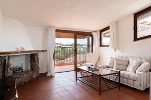 Ein Wohnzimmer mit Kamin aus Stein, einer Couch, einem Couchtisch und einem Balkon mit Blick.