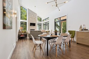 Ein modernes Interieur mit Essbereich, Sofa und großen Fenstern.