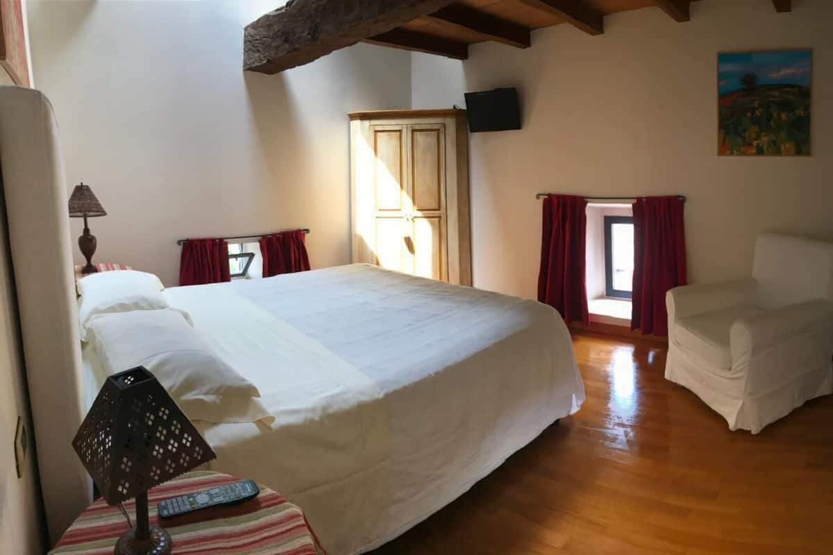 Une chambre à coucher avec un lit, une chaise, un téléviseur et un tableau accroché au mur.