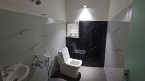 Casa de banho com sanita, bidé e lavatório, paredes de mármore e espelho.