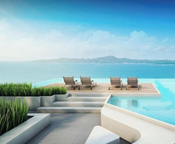 A poolside area with lounge chairs and a view of the sea. - Luxury Stay - Great Location & Sea View Room (Pattaya)