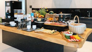 Un comptoir de buffet avec une machine à café, des fruits et divers aliments.