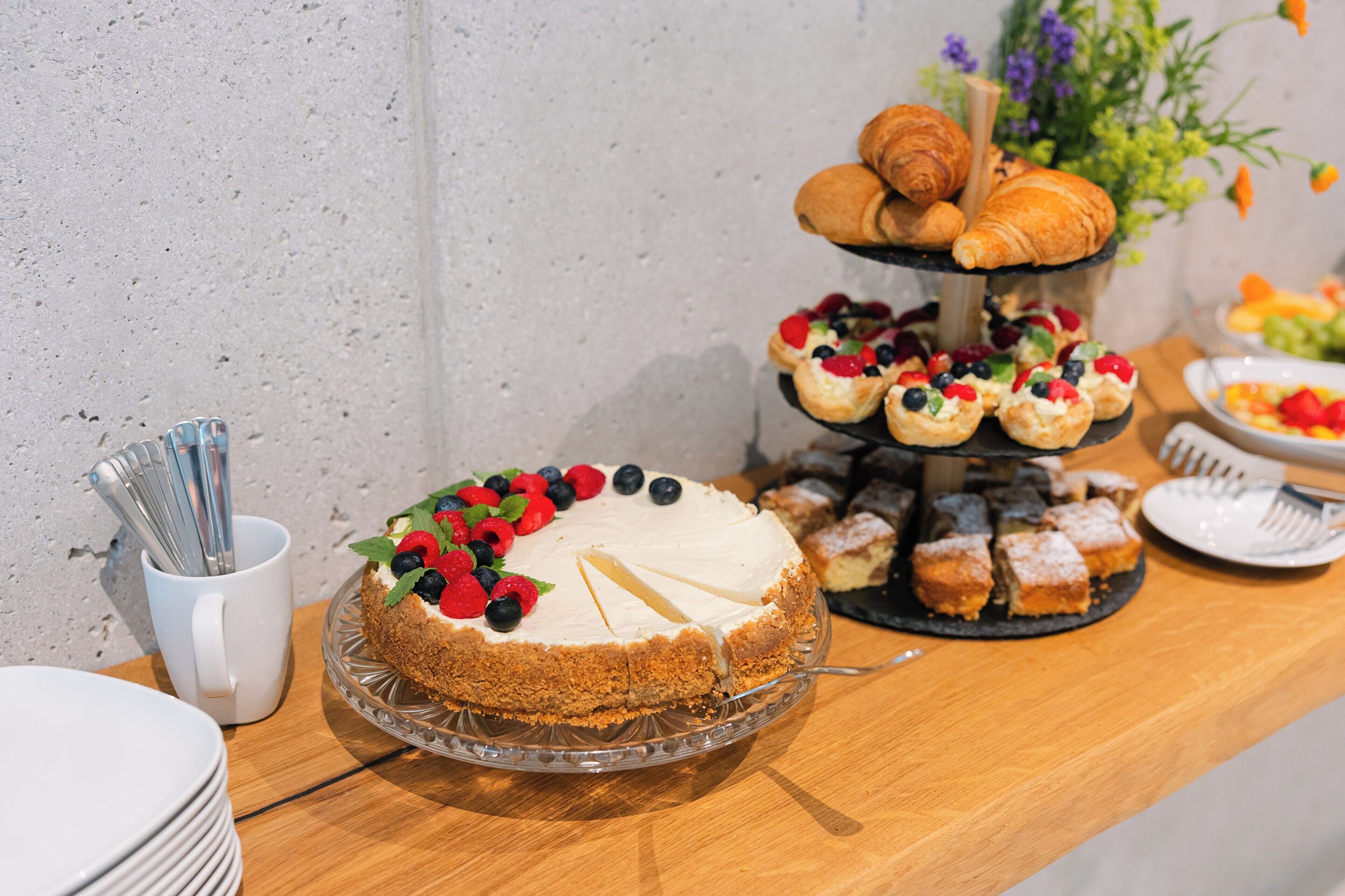 A dessert table with a cake, pastries, and fruit-topped pastries.