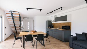 Une cuisine moderne avec une table à manger en bois, des chaises noires et un canapé noir.