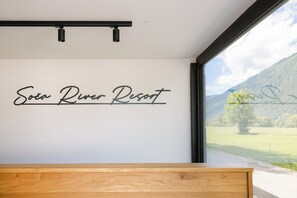 A wall with the text 'Soda River Resort' and a window with a view of a mountain and greenery. - Soča River Resort - Boutique Apartments (Tolmin)