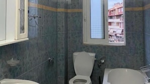 Baño con inodoro, lavamanos y bañera. Hay una ventana sobre el inodoro.