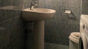 Un baño con lavamanos, espejo y lavadora.