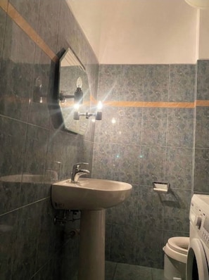 Ein Badezimmer mit Waschbecken, Spiegel und Waschmaschine.