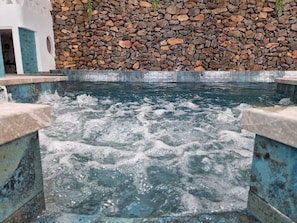 A hot spring with water flowing over rocks, surrounded by stone walls. - Gaviotas Beach Golf (El Ejido)
