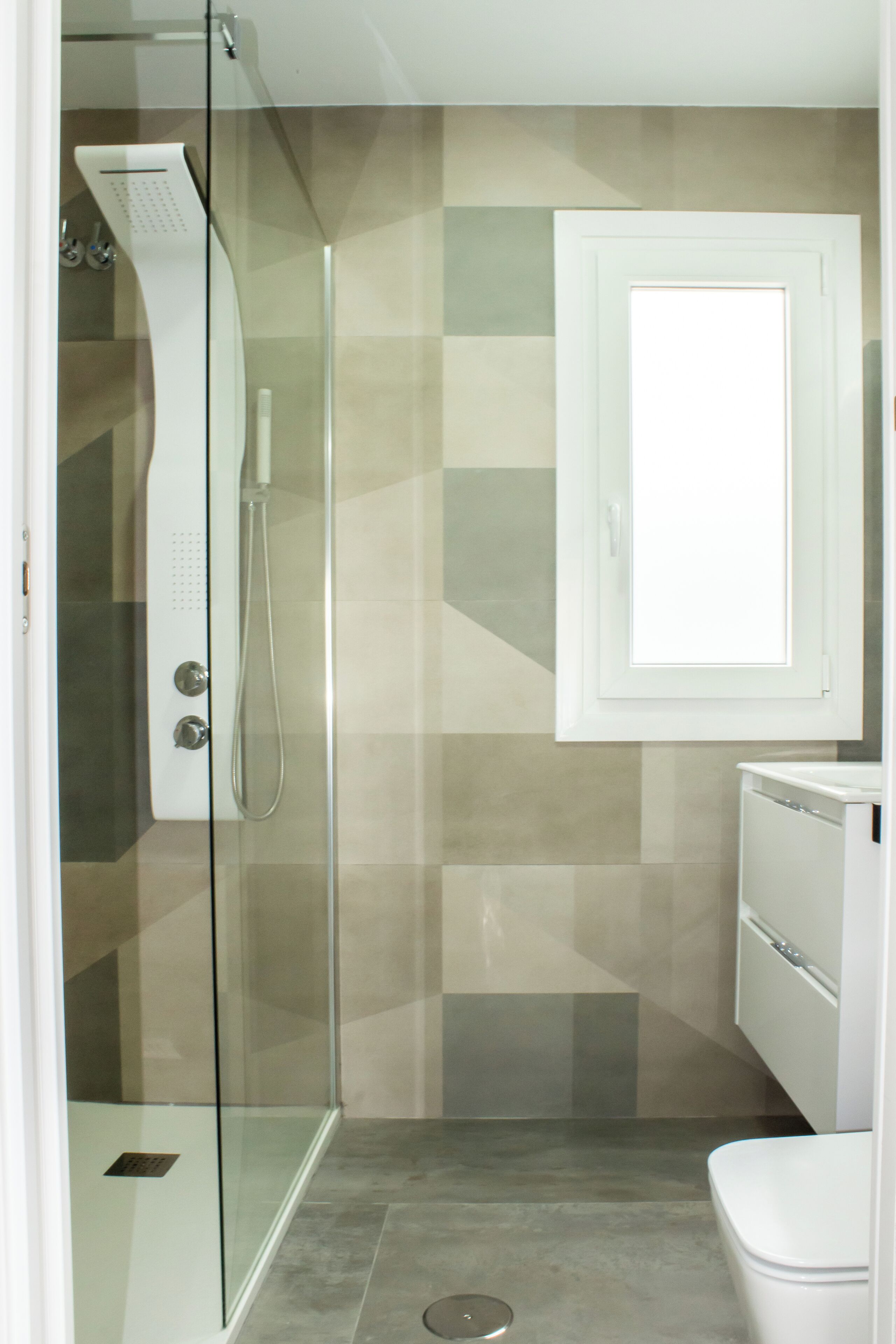 A bathroom with a glass shower enclosure, a toilet, and a cabinet.