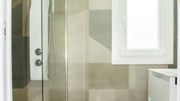 A bathroom with a glass shower enclosure, a toilet, and a cabinet.