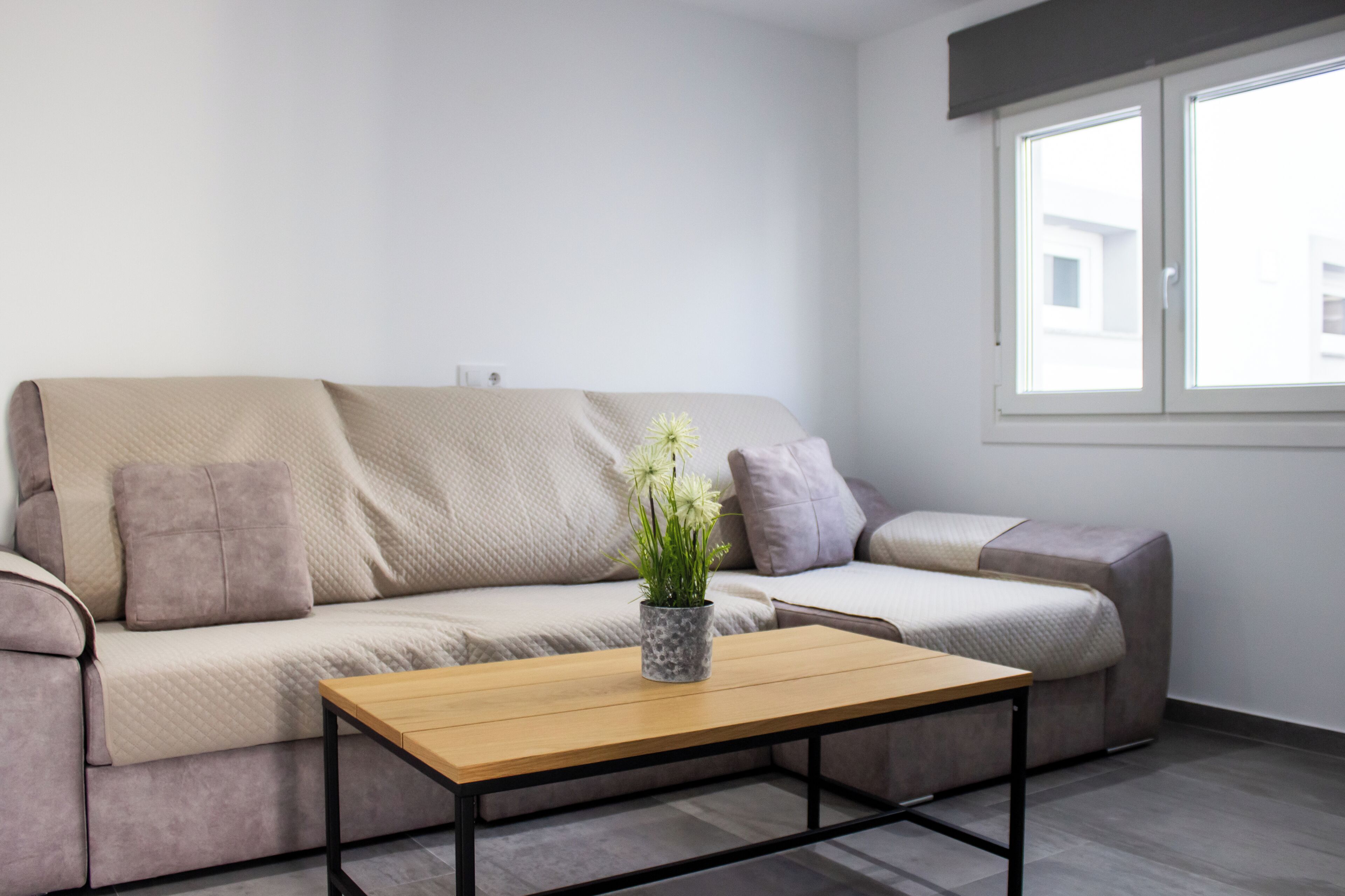 Un salon moderne avec un canapé, une table basse et une fenêtre.