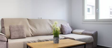 A modern living room with a sofa, a coffee table, and a window.