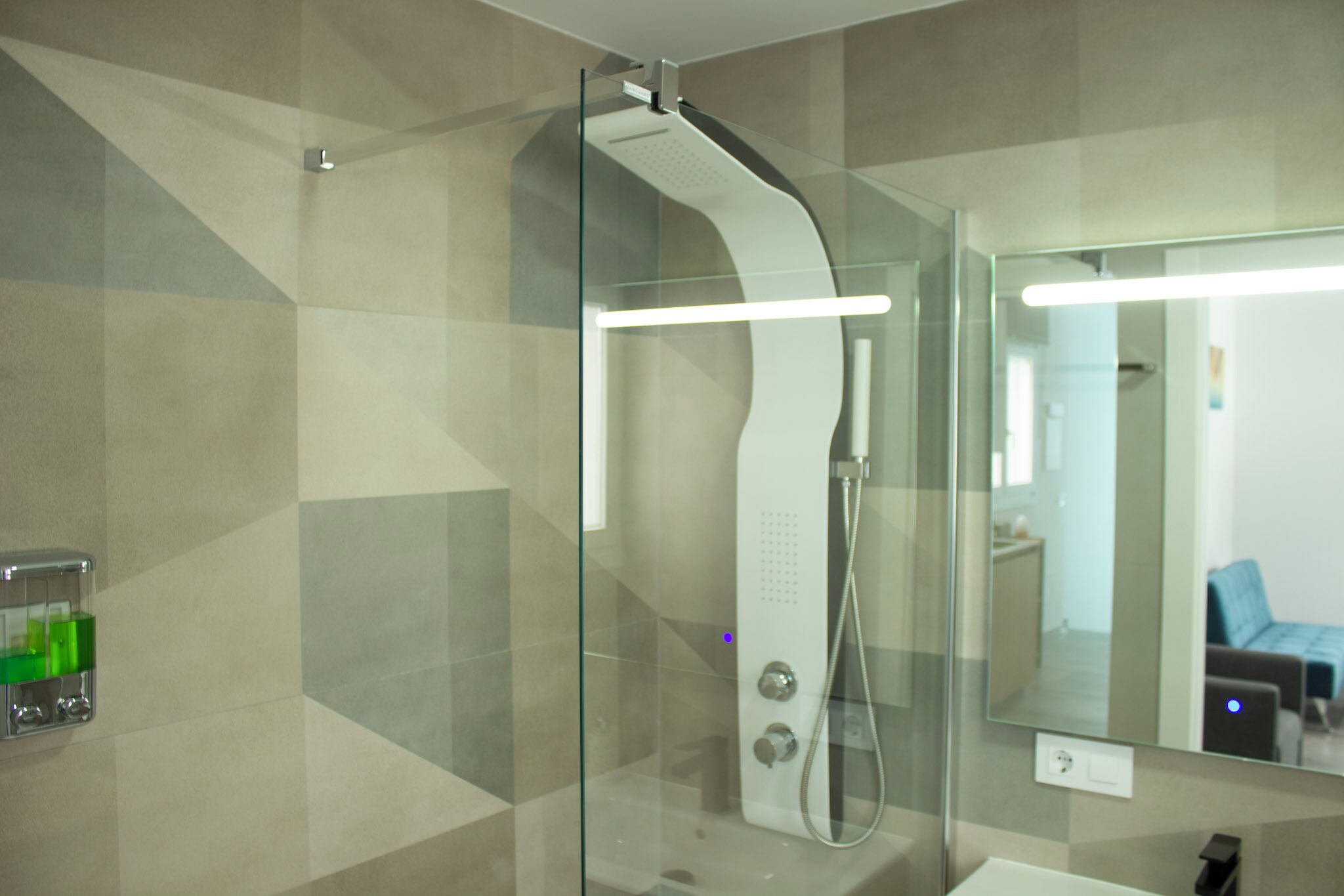Ein modernes Badezimmer mit einer gläsernen Duschkabine, einem gut sichtbaren Handtrockner und einem Spiegel, der den Raum reflektiert.