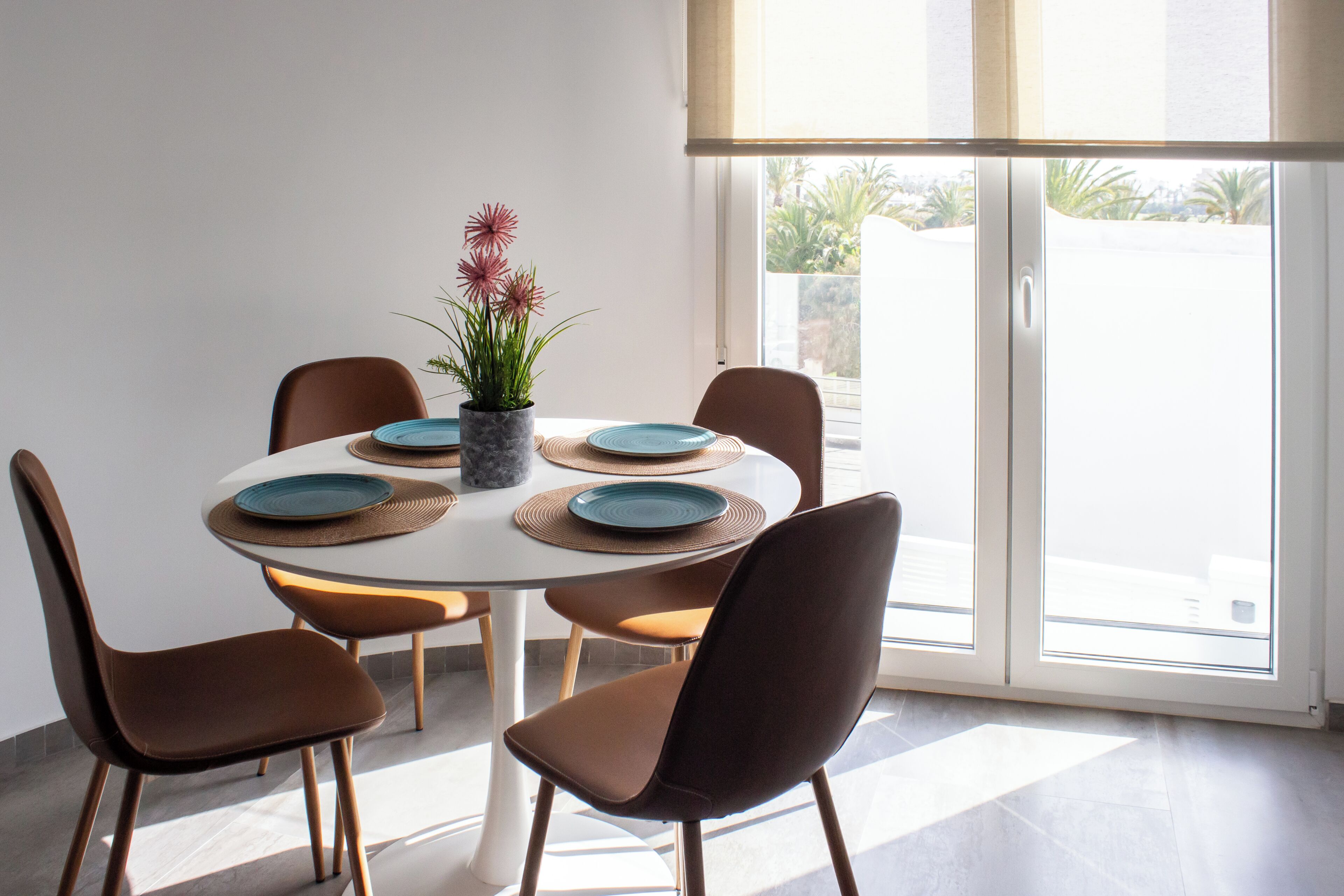 Un coin repas avec une table ronde, six chaises et une plante en pot.