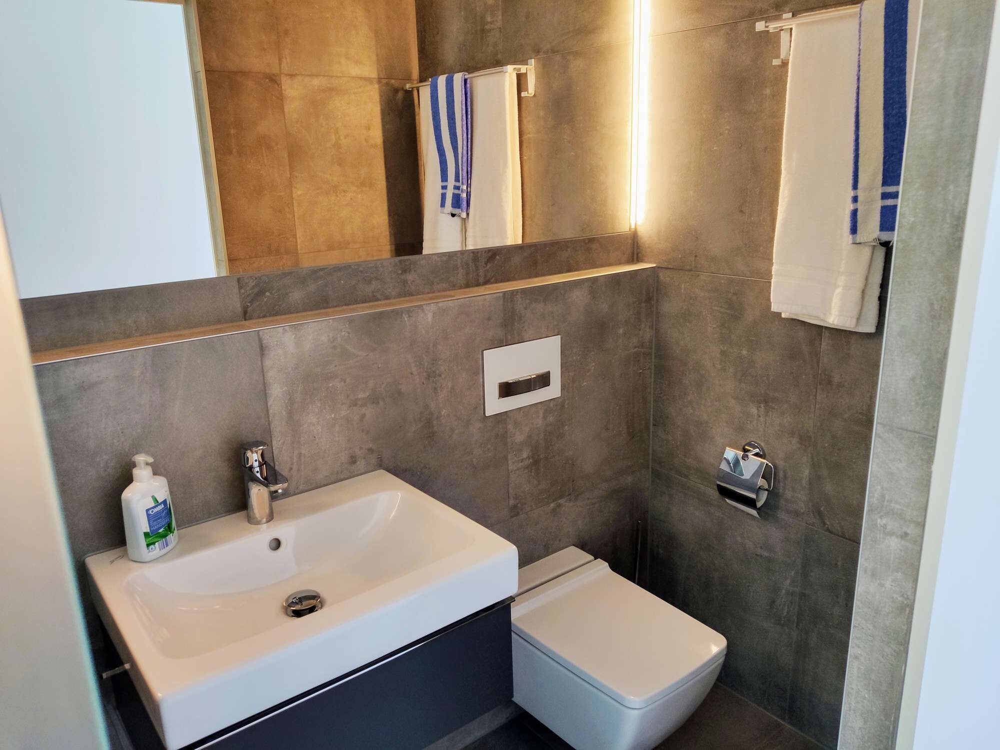 Ein Badezimmer mit einem weißen Waschbecken, einer Toilette und einem Spiegel.