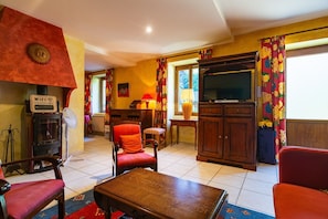 A living room with a fireplace, a television, and a dining area.
