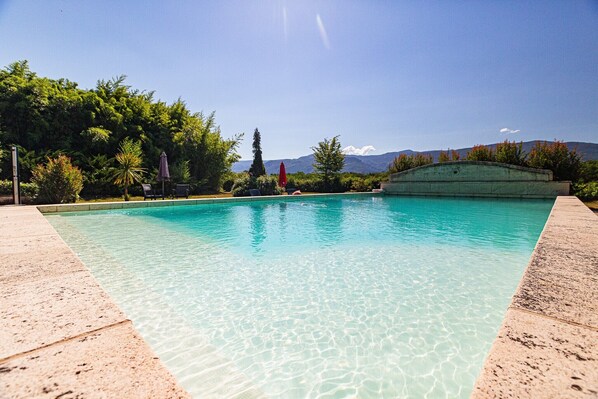Una piscina cristalina con vistas a montañas al fondo.