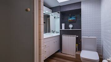 Un baño moderno con tragaluz, inodoro, lavamanos y espejo.