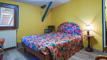 Quarto com cama, mesa de cabeceira, abajur e janela.