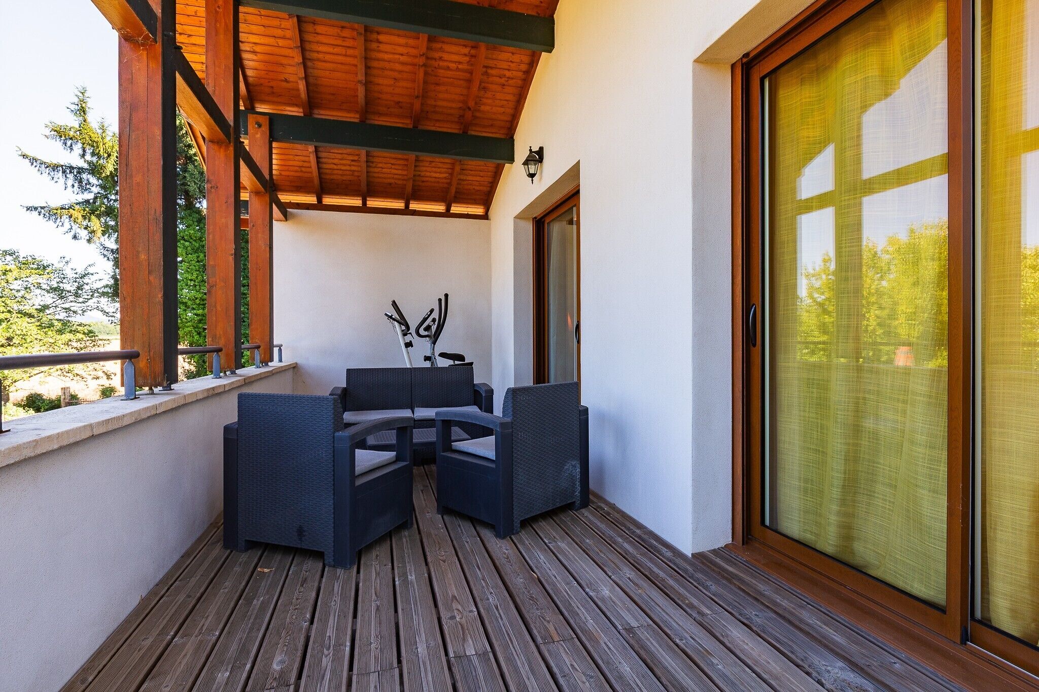 Un espacio de estar al aire libre techado con terraza de madera, una mesa y dos sillas.