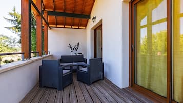 A covered outdoor seating area with a wooden deck, a table, and two chairs.