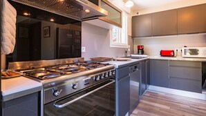 A modern kitchen with stainless steel appliances, a gas stove, and a built-in oven. - Gîte for 8 – La Fontaine Des Rollands: Mountain View, Shared Pool, Wi-Fi (Saint-Vérand)
