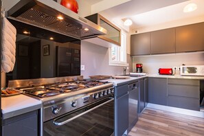 Une cuisine moderne équipée d’appareils électroménagers en acier inoxydable, d’une cuisinière à gaz et d’un four encastré.