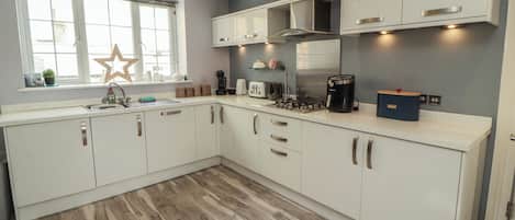Una cocina moderna con armarios blancos, estufa integrada y una ventana decorada con estrellas.