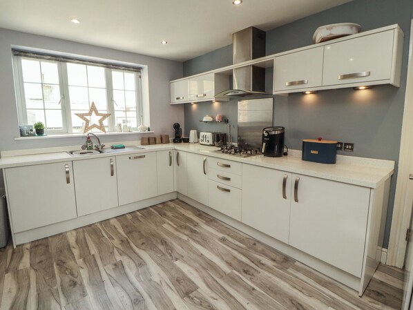 A modern kitchen with white cabinets, a built-in stove, and a window with a star decoration.