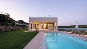A modern house with a swimming pool, outdoor seating, and a view of the landscape. - Villa Neratzia-Luxury Escape (Neratzia)