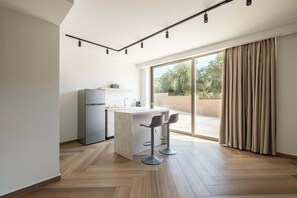Eine moderne Küche mit integrierter Kücheninsel, Barhocker und einer Schiebetür zu einem Balkon.