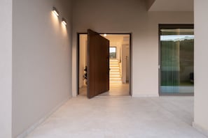 Ein moderner Flur mit einer Holztür, einer Treppe und einer Glastür zum Außenbereich.
