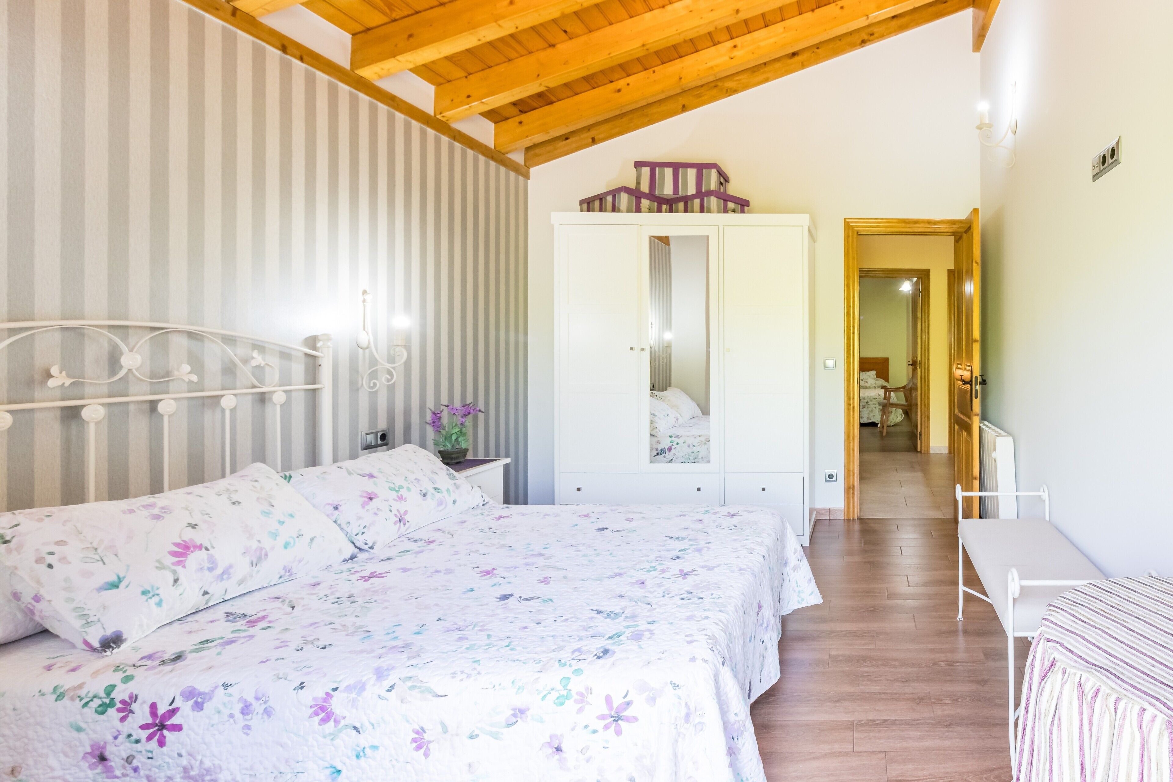 Un dormitorio con una cama, un armario, una mesita de noche y una pequeña mesa.