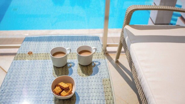 A poolside area with a table, two cups of coffee, and a bowl of cookies. - Premium 4 Bedroom Villa in Oludeniz (Fethiye)