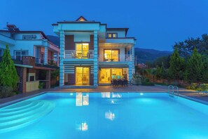 Uma casa de dois andares com uma piscina em frente.