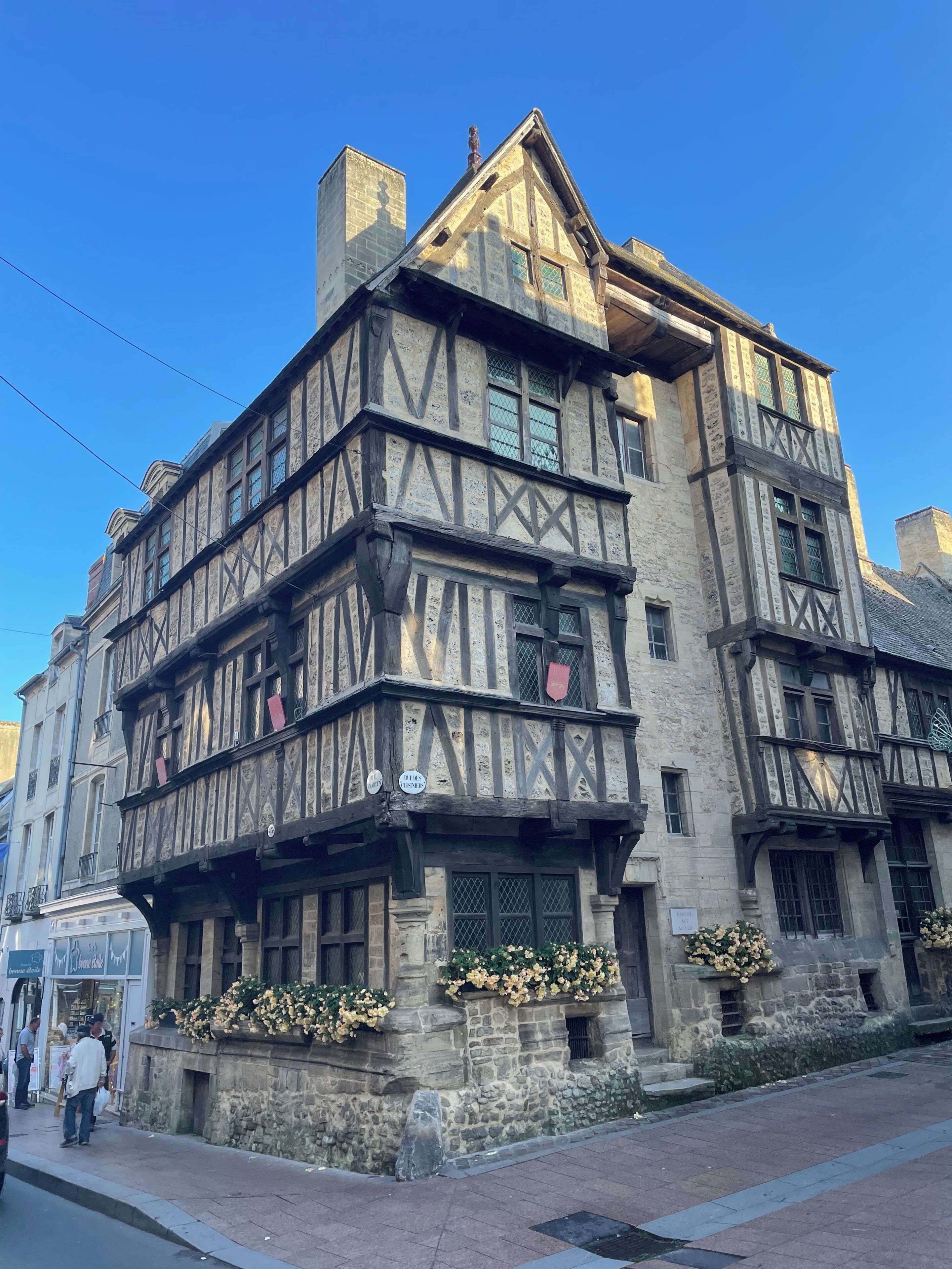 Un bâtiment historique à la façade à colombages, doté d’une base en pierre et de jardinières fleuries.