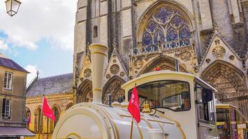 A vintage train with a license plate GF-498-KH parked in front of a Gothic cathedral.